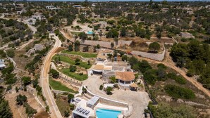 Vista aérea de una zona residencial con piscina, senderos de piedra y casas dispersas.