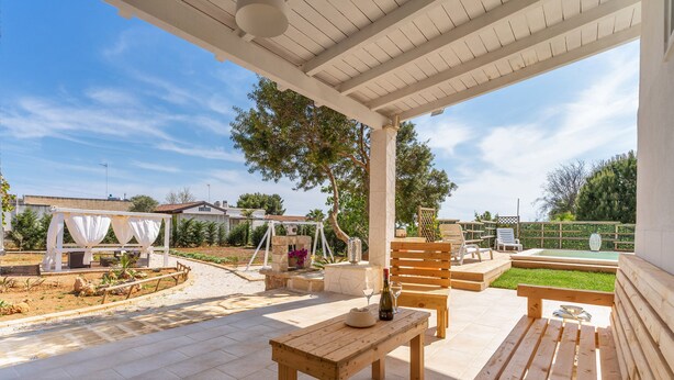 An outdoor patio area with a wooden table, benches, and a pergola. - Villetta Marcella (Racale)