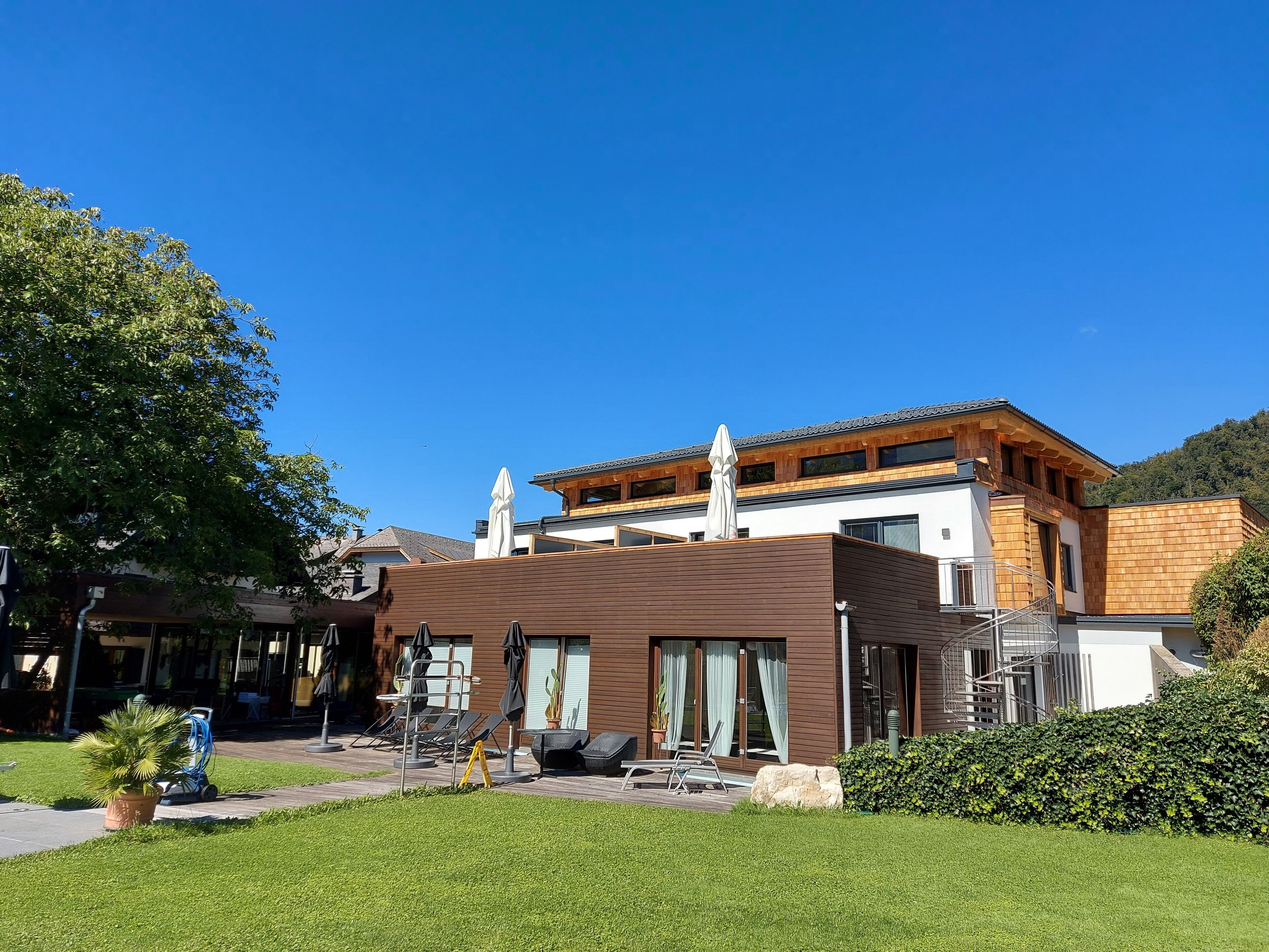 A modern building with a wooden facade, large windows, and outdoor seating.