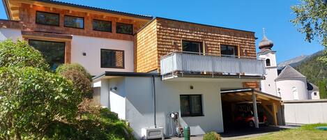 Una casa moderna con un garaje amplio, un balcón y una iglesia al fondo.