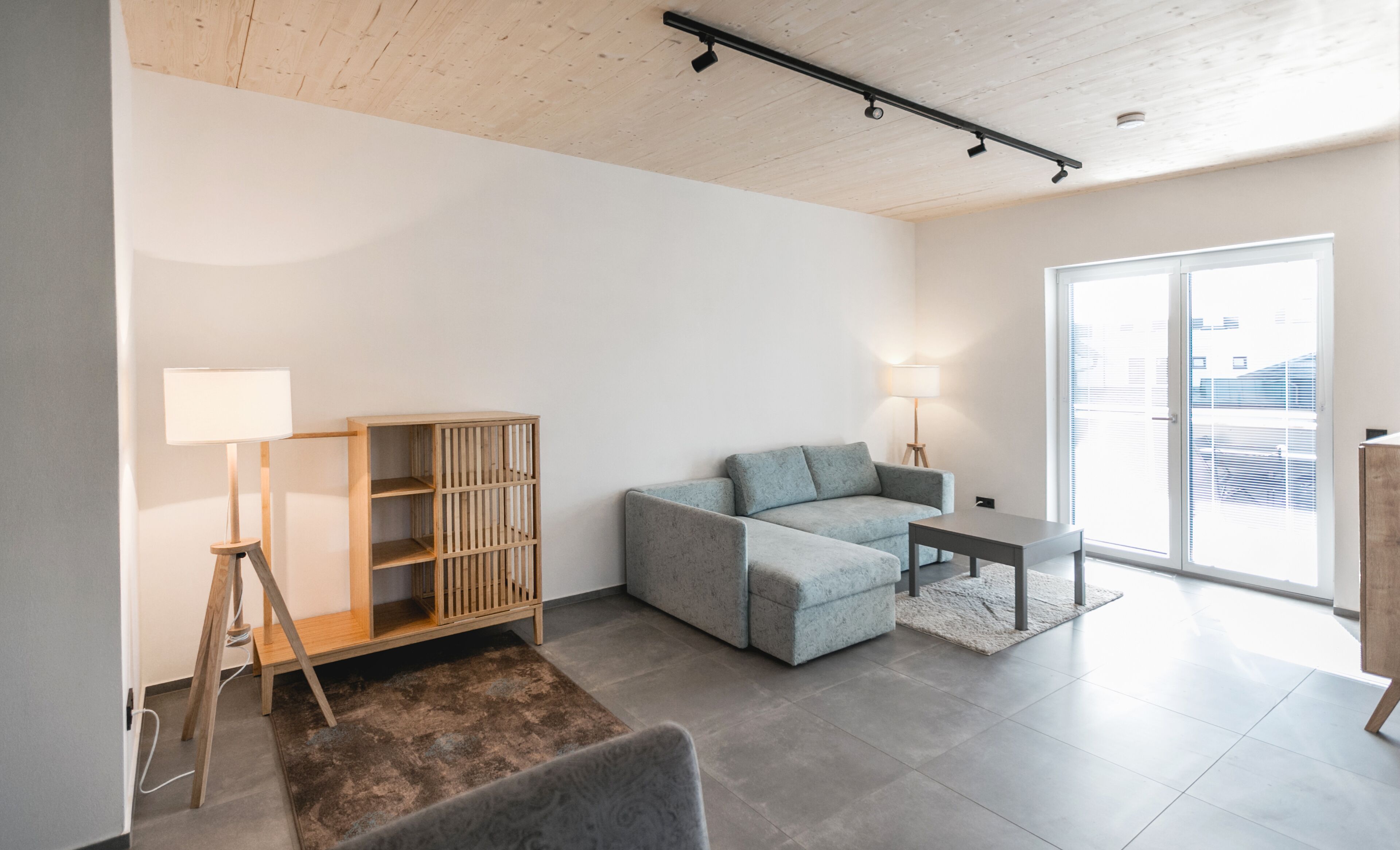 A modern living room with a sofa, a wooden cabinet, a small table, and a floor lamp.