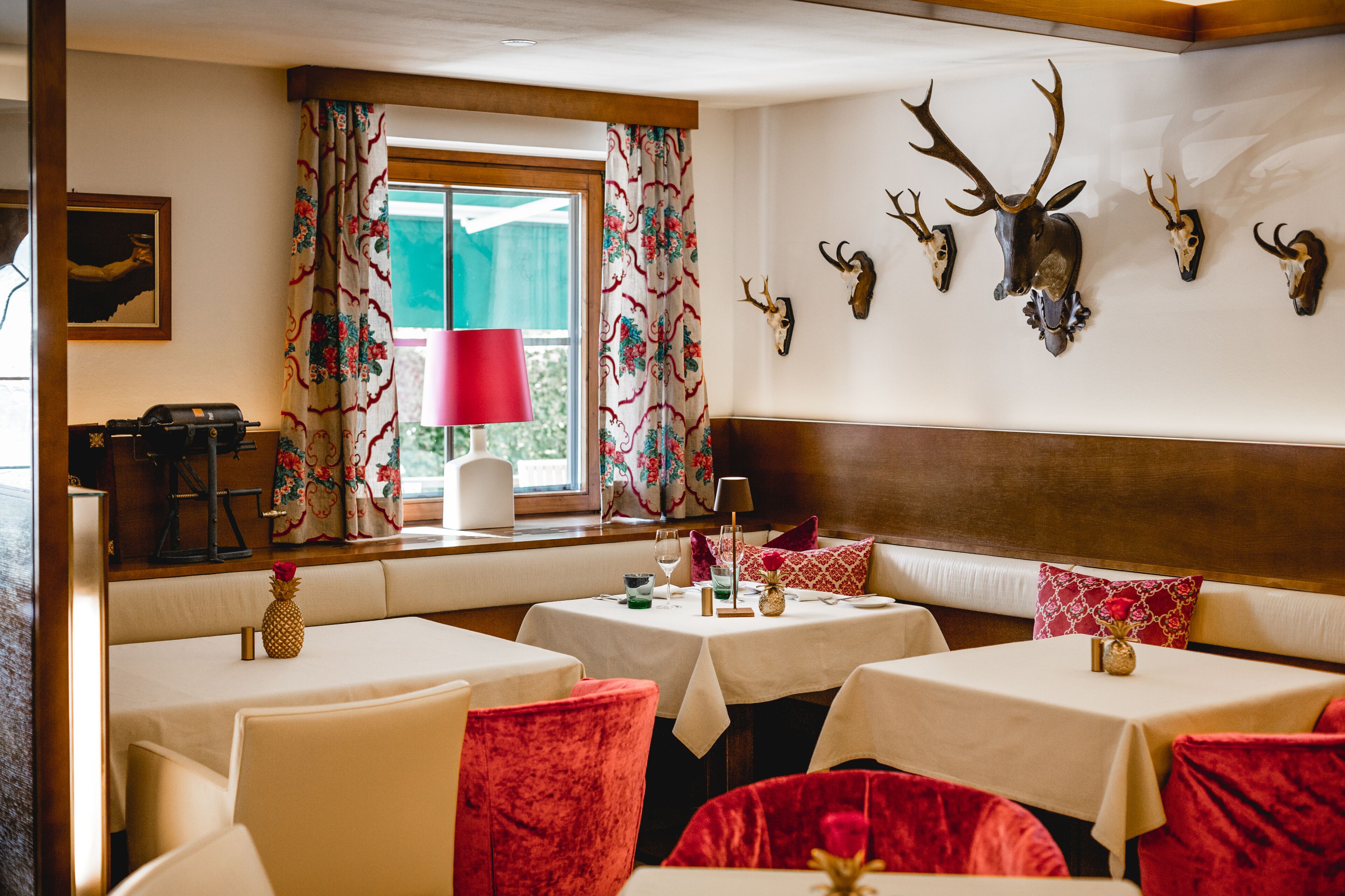 A dining area with booths, a window with curtains, and mounted animal skulls on the wall.