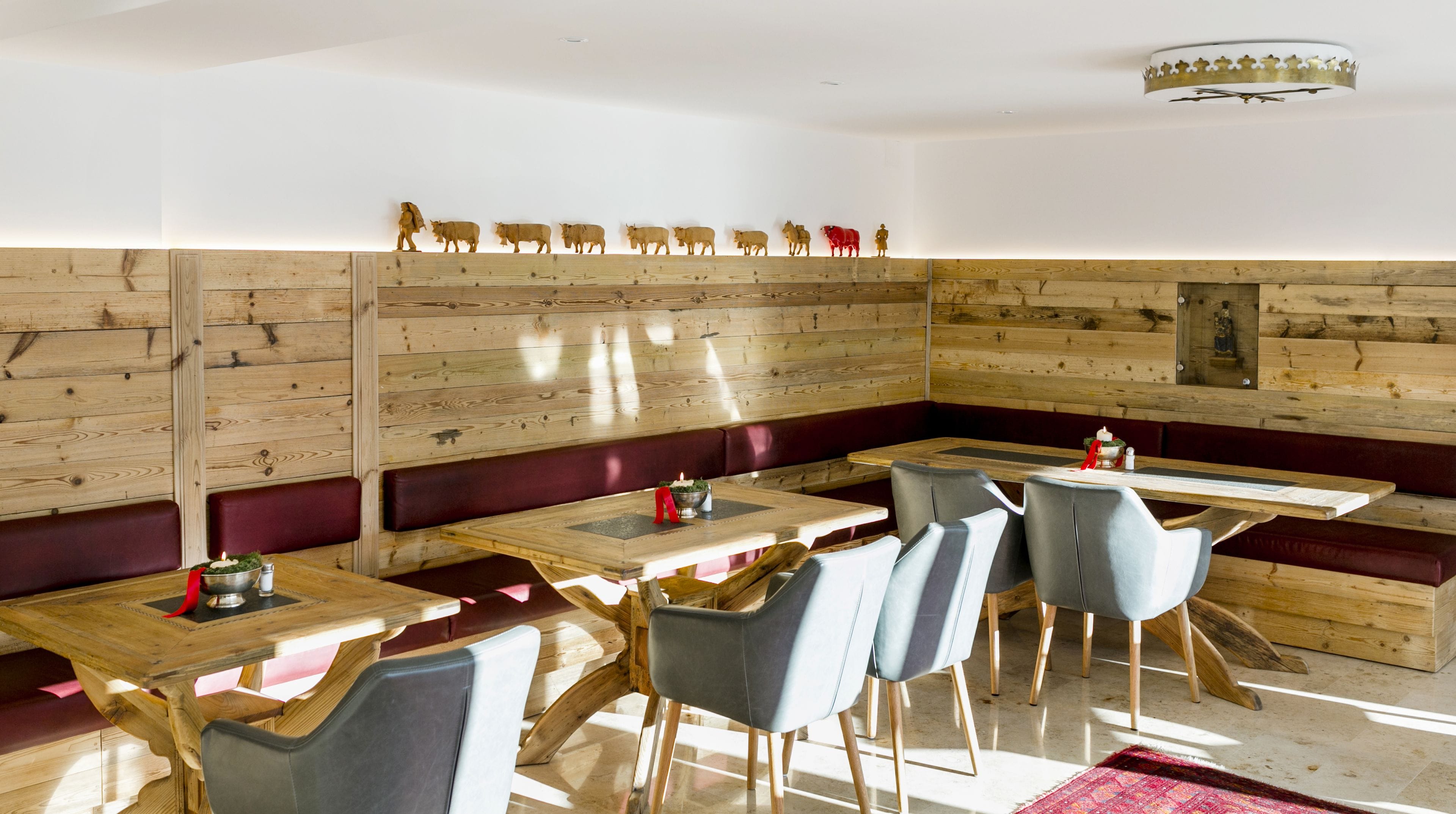 A restaurant with wooden panel walls, red cushioned booths, and a long wooden table with chairs.