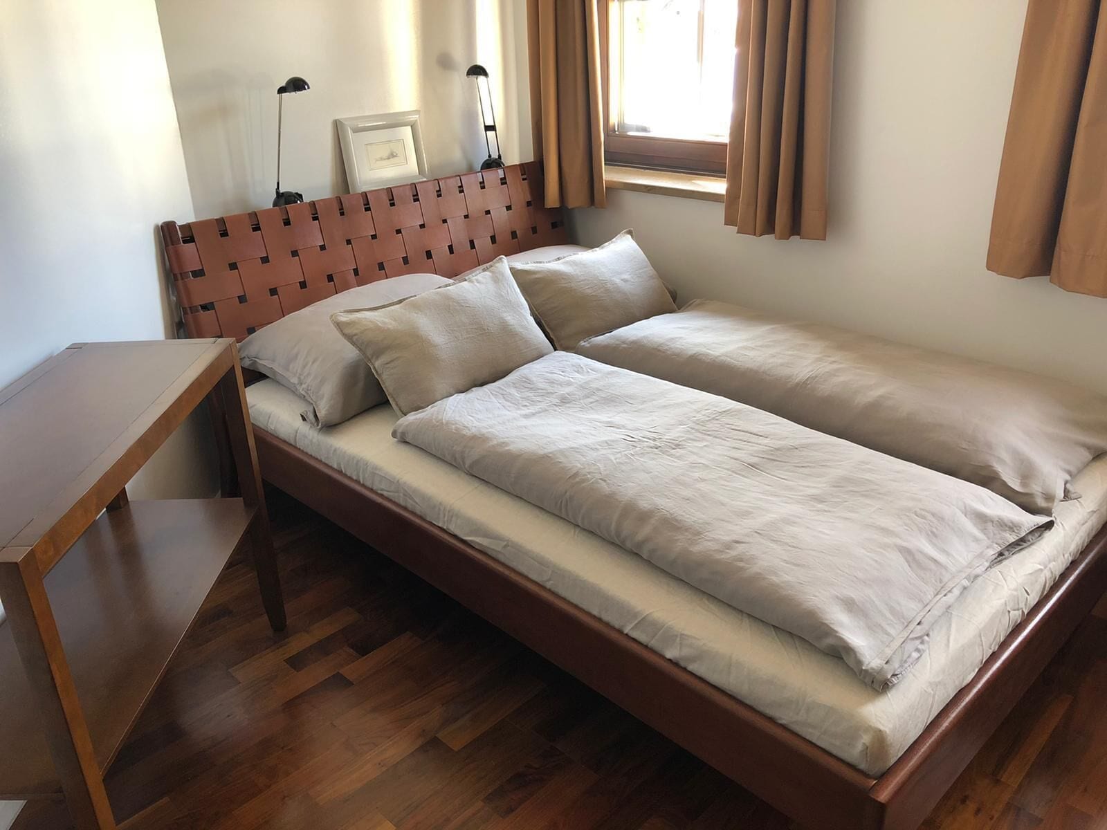 Una cama individual con cabecera y mesita de noche de madera a la izquierda.