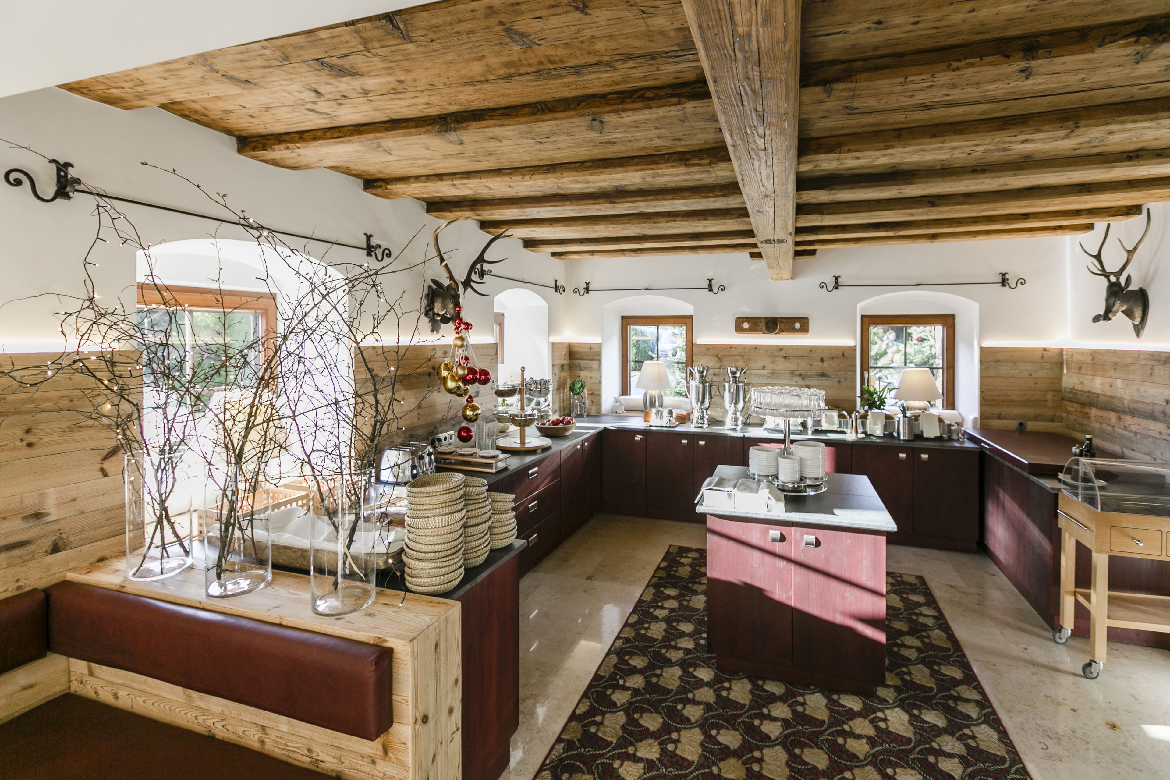 A rustic kitchen with wooden beams, a central island, and decorative antlers.