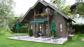 A two-story house with a deck, outdoor seating, and a covered porch.