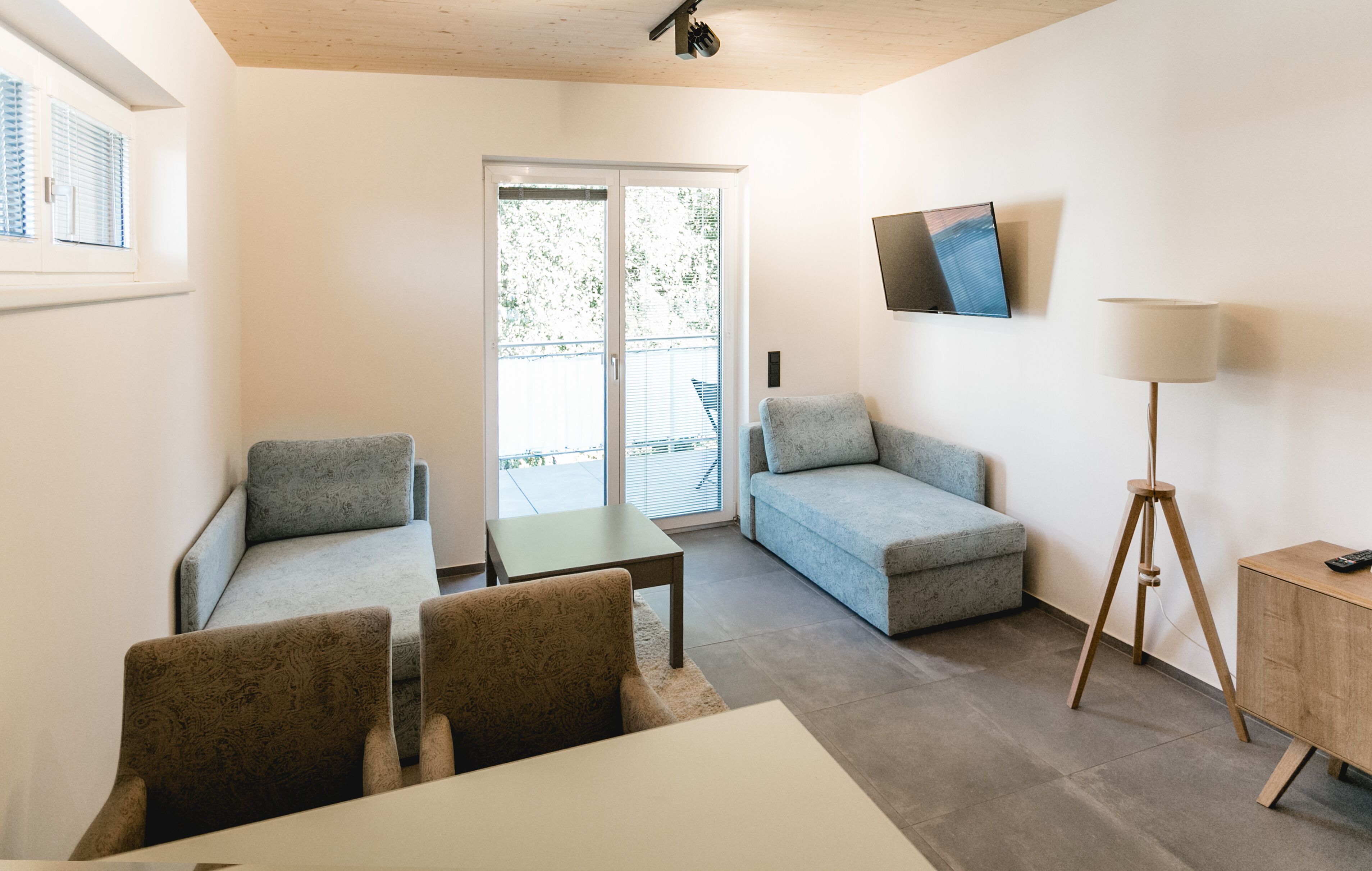 Una sala de estar moderna con un sofá, sillones, una mesa de centro, un televisor y una lámpara.