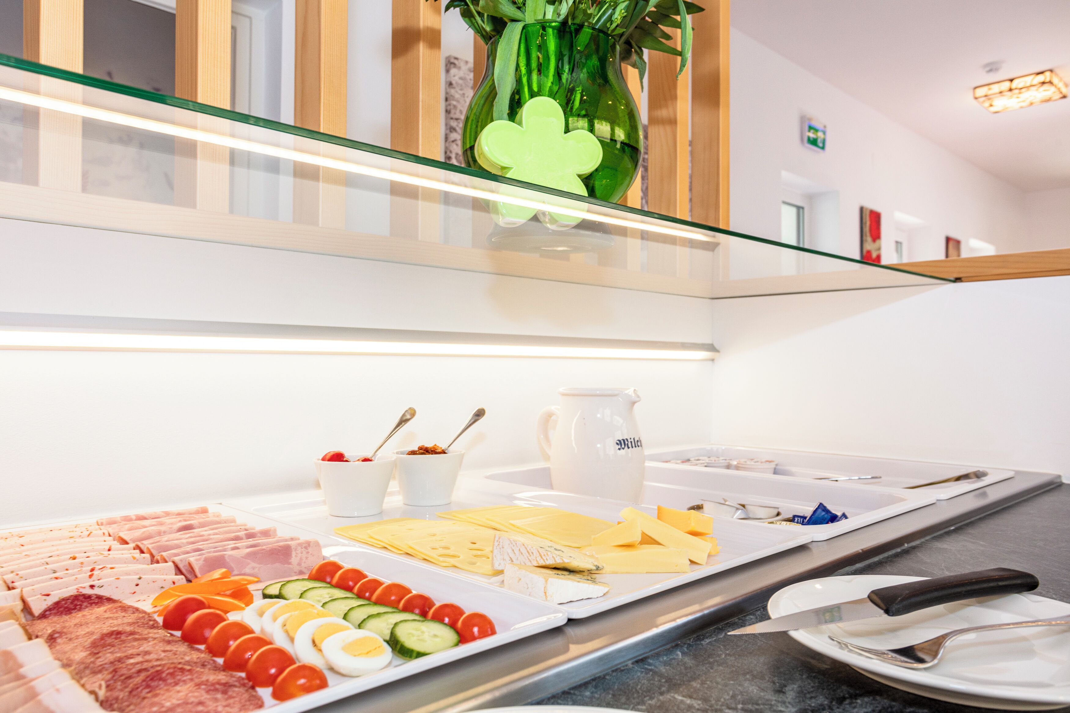 Disposición de un bufé con diferentes alimentos, una jarra y un cuchillo sobre una encimera.