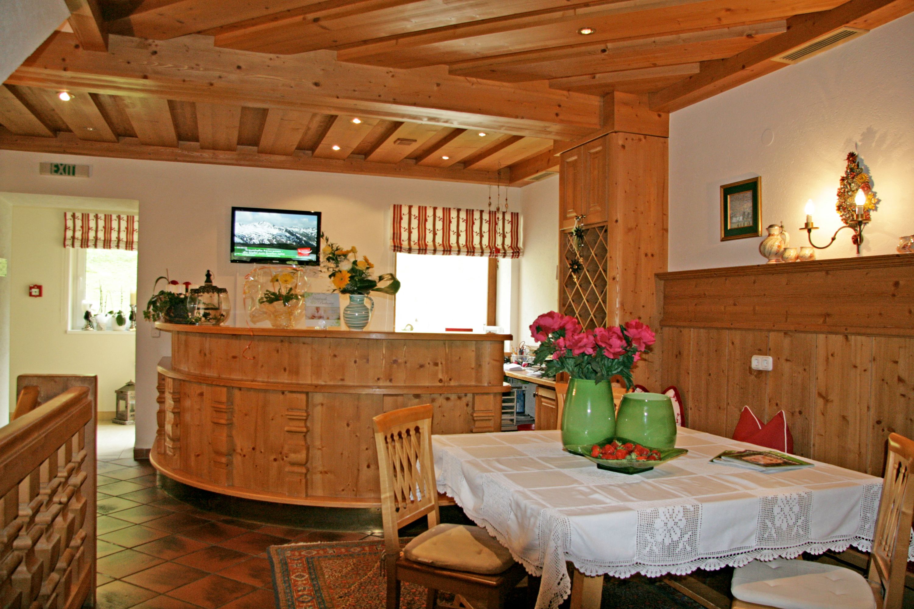 A wooden interior with a round bar, white tablecloth-covered dining table, and chairs.