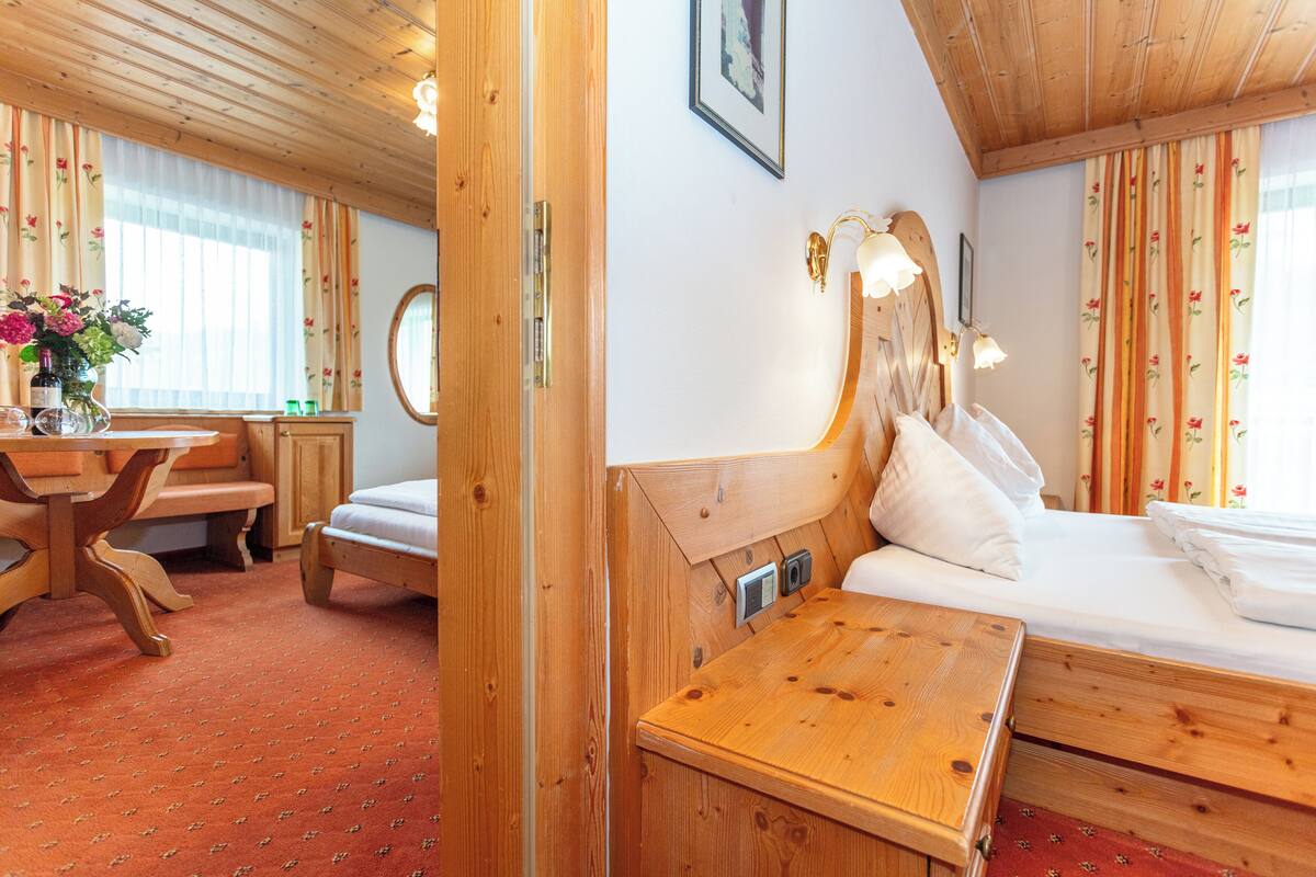 A wooden-framed room with a bed, a wooden table, and a desk with a chair.