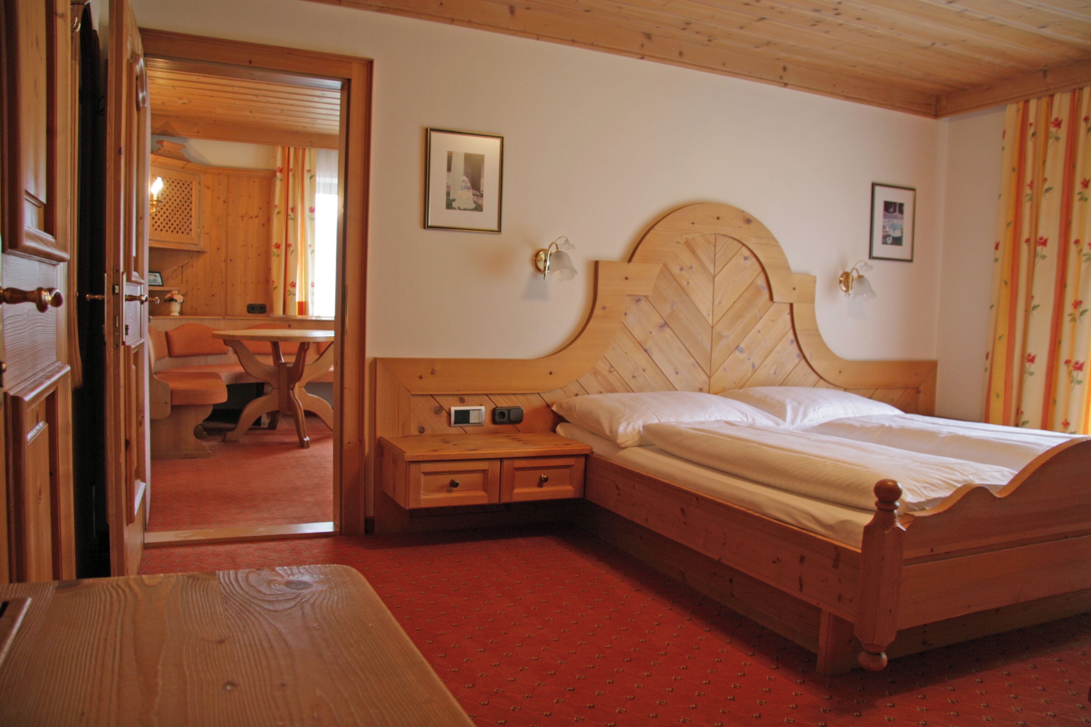A wooden bed with a headboard, bedside tables, and a red carpeted floor.