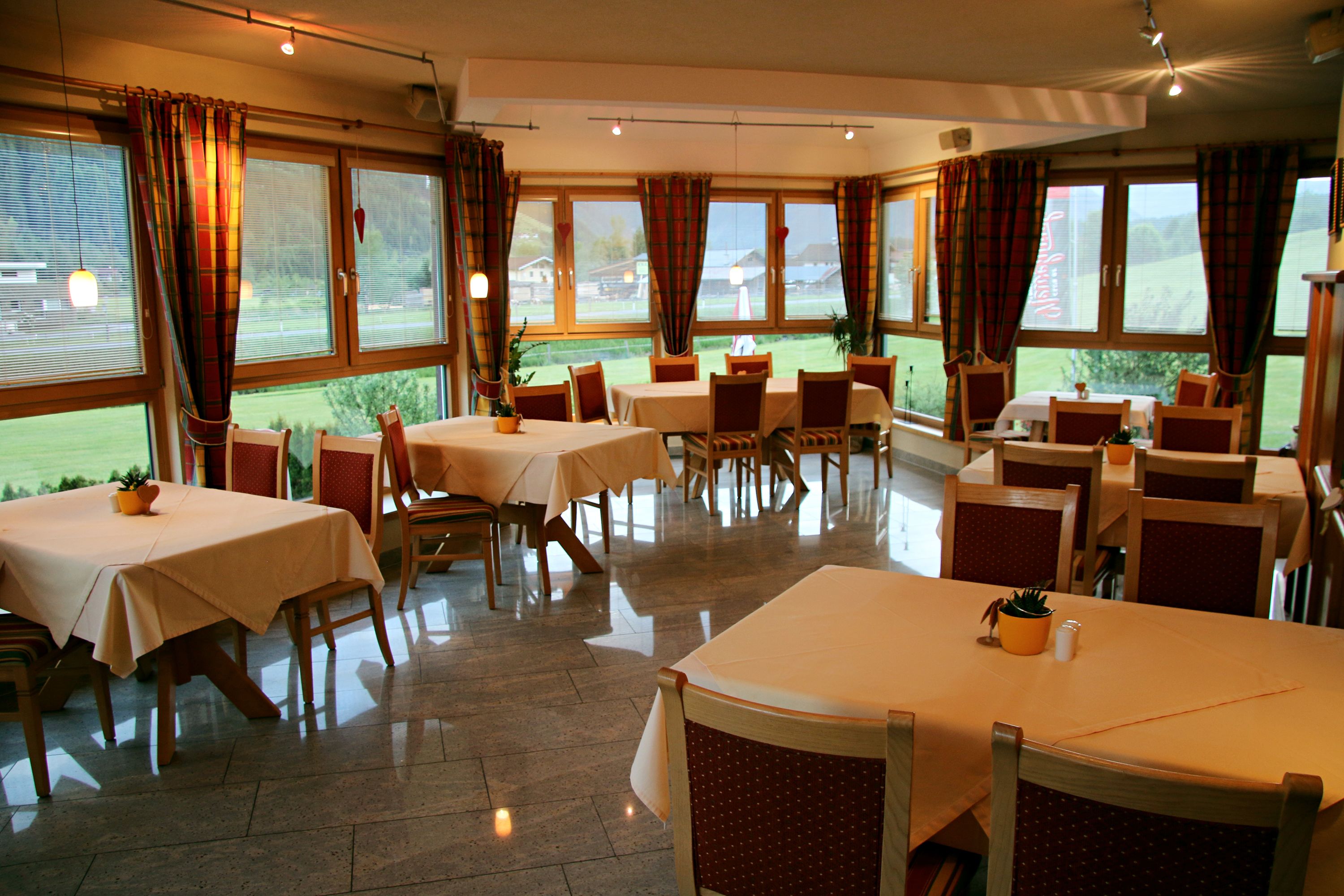 Un restaurant doté de nombreuses tables et chaises, de grandes fenêtres et offrant une vue sur l’extérieur.