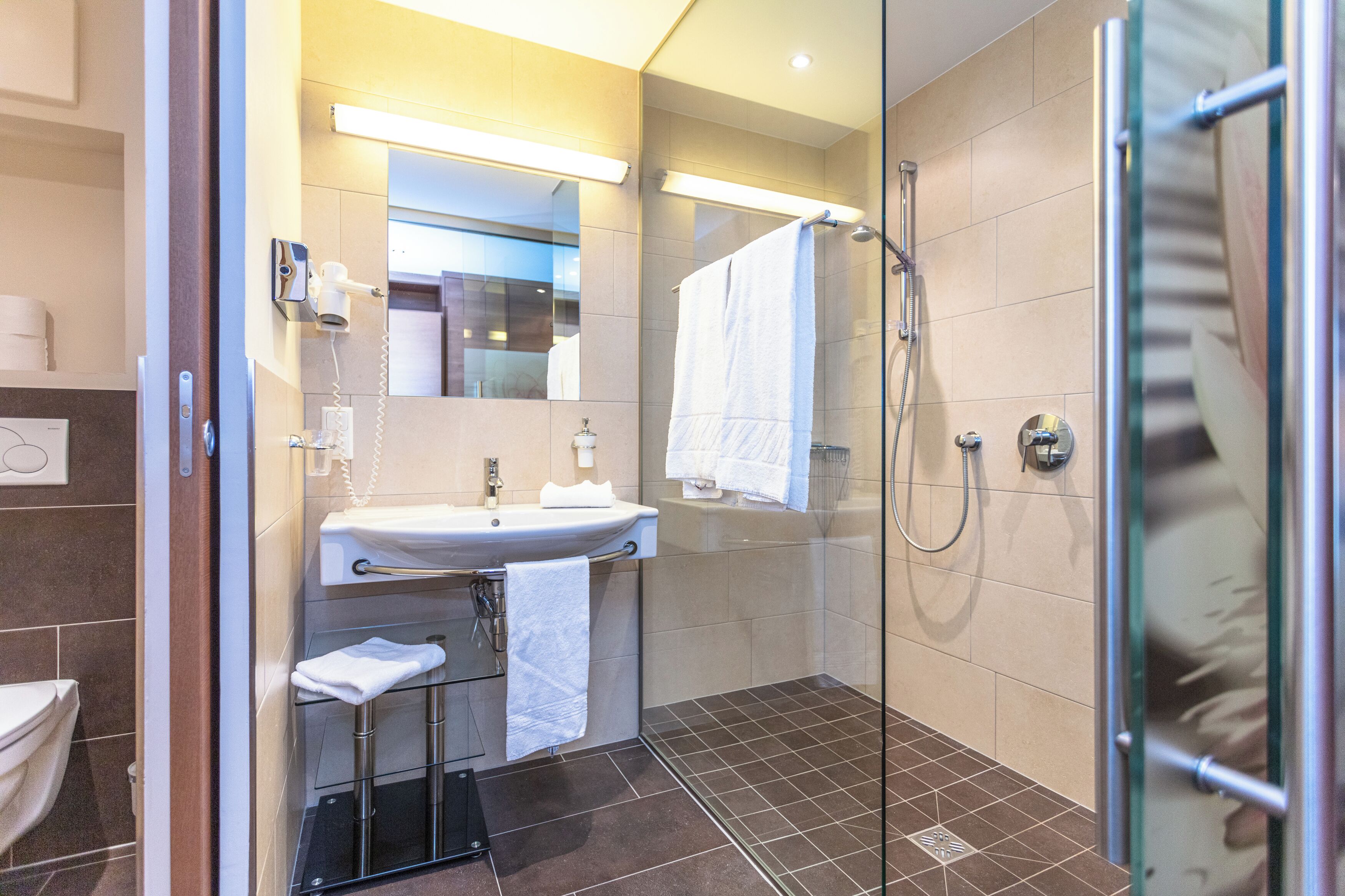 A modern bathroom with a glass shower enclosure, a sink with a towel rack, and a mirror above the sink.