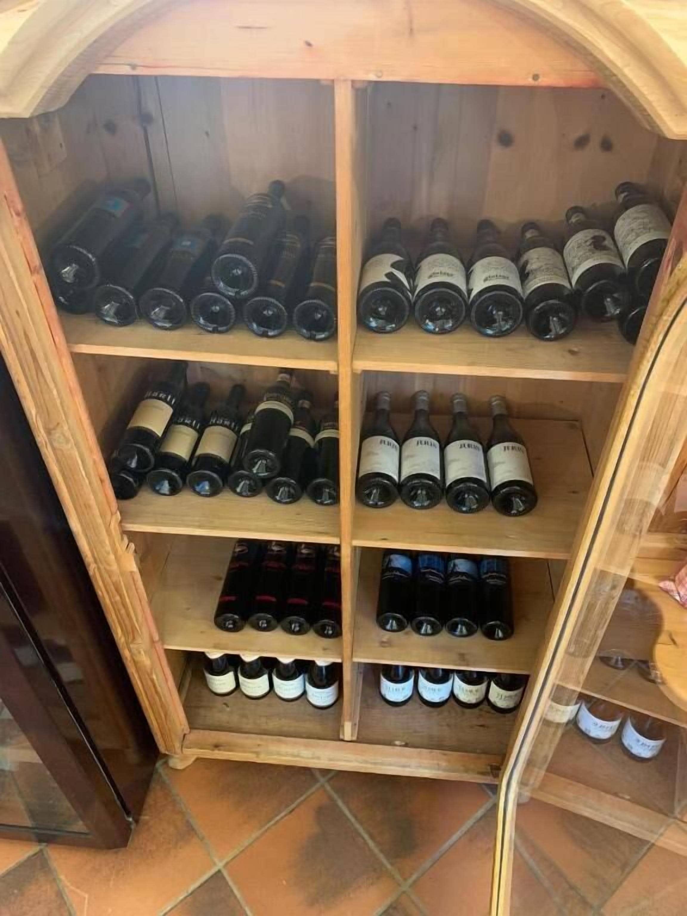 A wine cellar with multiple wooden shelves holding wine bottles.