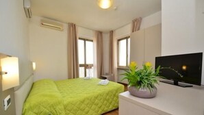 Une chambre d’hôtel avec un lit, une télévision, un bureau et une fenêtre.