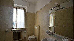 Une salle de bain équipée de toilettes, d’un lavabo, d’un miroir et d’une fenêtre avec des rideaux.