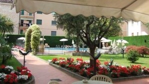 Un espace extérieur aménagé avec un patio couvert, un arbre et des parterres de fleurs.