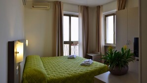 Una habitación de hotel con una cama, un escritorio, una planta en maceta y un televisor.