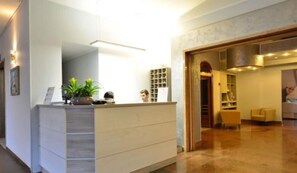 Un espace d’accueil avec un comptoir, des plantes et une bibliothèque.