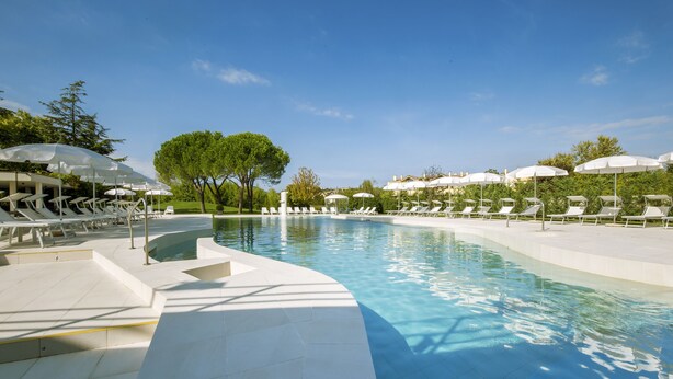 A swimming pool with sun loungers and umbrellas, surrounded by trees and buildings. - Hotel Smeraldo (Abano Terme)