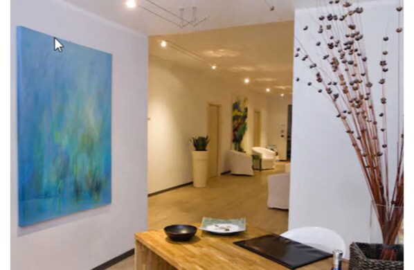 A modern interior with a large abstract painting, a wooden reception desk, and a decorative plant arrangement.