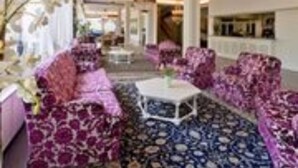 A hotel lobby with patterned sofas, a central coffee table, and a chandelier. - Hotel Smeraldo (Abano Terme)