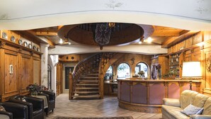 A spacious living area with a grand staircase, wooden paneling, and a cozy seating arrangement. - Sporthotel Spögler (Renon)