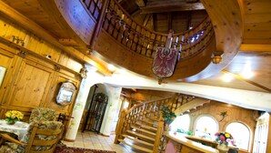 A wooden interior with a curved staircase, a dining area with a table and chairs, and a decorative emblem on the wall. - Sporthotel Spögler (Renon)
