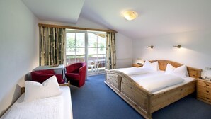 Ett hotellrum med två separata sängar, ett skrivbord, en stol och ett fönster med gardiner.
