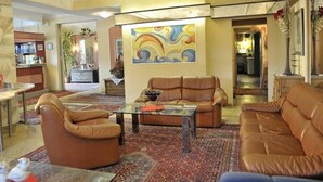 A spacious living room with leather sofas, a glass coffee table, and a colorful abstract painting on the wall. - Zum Stadttor (Schladming)