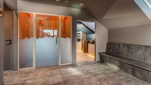 A modern interior with a wooden sliding door, a bench, and a view of a kitchen area. - Zum Stadttor (Schladming)