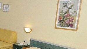 A double bed with a green headboard, a bedside table with a lamp, and a framed floral painting on the wall. - Zum Stadttor (Schladming)
