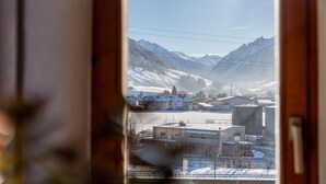 Une vue à travers une fenêtre sur une ville de montagne enneigée, avec ses bâtiments et ses lignes électriques.