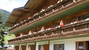 A traditional wooden chalet with multiple balconies adorned with flowers, set against a mountainous backdrop. - first mountain Hotel Zillertal (Aschau Im Zillertal)
