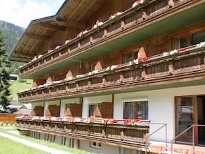 Una cabaña de madera tradicional con varios balcones decorados con flores, con montañas al fondo.