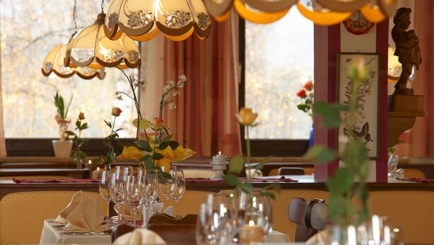 Una mesa de comedor decorada con varias copas de vino, un florero con flores y una lámpara en el techo.