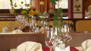 Una mesa de comedor adornada con copas de vino, un florero con flores y un candelabro.
