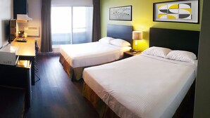 A hotel room with two beds, a desk, a lamp, and artwork on the walls. - Home Away Inn (Drayton Valley)