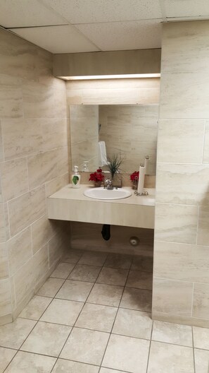 A bathroom with beige tiles, a sink, a mirror, and a towel rack.