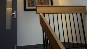 A staircase with a wooden handrail and black balusters, leading to a landing with a skylight above. - Home Away Inn (Drayton Valley)