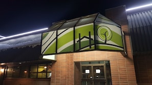 A hotel entrance with a green and white facade, a visible sign indicating 'Hotel Staff Only' access, and a brick exterior.