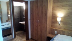 Een slaapkamer met een houten garderobe, een nachtkastje, een bed en een wandlamp.