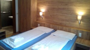 Een kamer met twee bedden, houten paneelwanden en wandlampen.