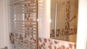Een badkamer met een douche, wastafel en een glazen deur.