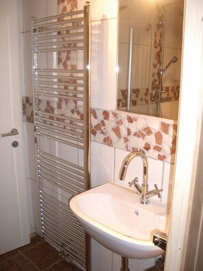 A bathroom with a shower, a sink, and a glass door.