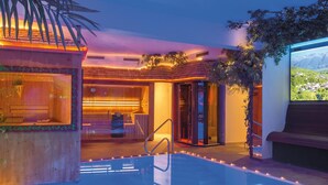 A pool area with a hot tub, a bar, and a view of a mountainous landscape. - Hotel Engel (Sluderno)