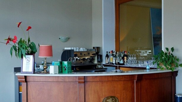 A bar area with a coffee machine, bottles, glasses, and a mirror. - Europa (Ispra)