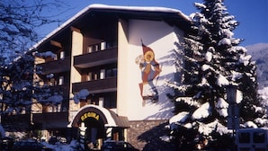 Un edificio con un murale a tema sciistico, un cartello con la scritta "REGINA" e un paesaggio innevato.