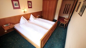 Un letto matrimoniale con testiera in legno, un comodino, un armadio e un tavolino con una sedia.