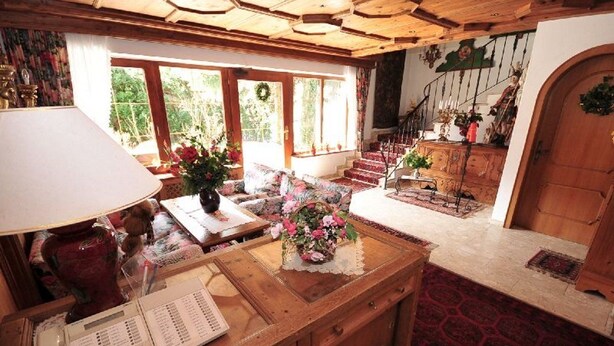 Una camera accogliente con una scrivania in legno, un telefono e un vaso di fiori. Una scala conduce a un piano superiore con vista sul verde circostante.